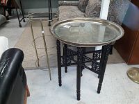 Two side tables shown together: a gold-tone metal tiered base table missing glass and a black Chinoiserie wood base side table with metal and glass top.