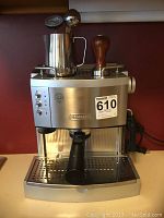 Full front view of the DeLonghi espresso and cappuccino machine showing stainless steel and black plastic body with control panel and portafilter holder.