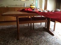 Side angle view of the Danish Modern teak dining table showing worn leg and base.