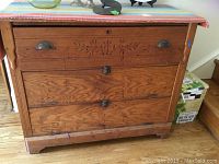 Front view of antique oak chest showing two drawers on top with brass cup pulls, carved floral design on upper drawer, and two pull-down doors below with latch hardware.