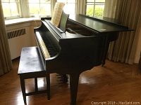 Side angled view of the black lacquer Haines Brothers baby grand piano with bench in a well-lit room showing wood floor and window curtains.