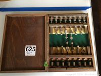 Full view of open wooden case showing metal chess pieces in their compartments.
