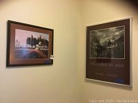 Wall corner with two framed artworks: left a colored landscape print and right a silver metal framed Ansel Adams photographic print titled 'The American West' Galerie Zabriskie.