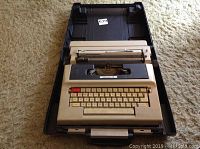View of vintage Underwood 478 electric typewriter inside black carrying case on carpeted floor, showing keyboard and top portion.