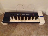 Full view of Realistic Concertmate 660 keyboard with music stand attached and foam packaging blocks on both ends.