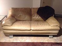 Full front view of tan leather Italsofa sofa with visible use and brown throw on one arm. Sofa shows creases and wear marks on cushions. Chrome legs visible under sofa.
