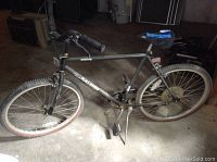 Full side view of the black Raleigh men's bicycle showing frame, tires, seat, kickstand and handlebars.