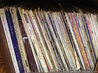 Photo showing vinyl records tightly packed vertically on a shelf, covers visibly worn with titles including Beethoven and rock albums.