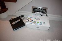 Nintendo Wii Sports game box with instruction manual and coiled cables beside Digitron DVD player with remote on top.