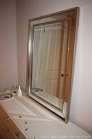 Front view of the bevel edge pieced glass mirror placed on a cabinet with reflection of a door.
