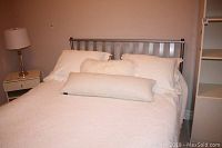 Full view of queen bed made with silver metal frame including headboard and footboard, mattress, pillows, and white bedding for demonstration.