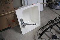 View of white square fiberglass laundry sink with chrome faucet, showing light stain at bottom interior and attached faucet on side.