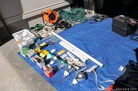 View of all items on blue tarp showing electrical cables, light bulbs, extension cords, and power bars