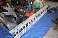 Full view of 16 ft aluminum extension ladder with two sections laid out on blue tarp.