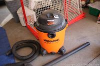 Shop-Vac brand orange 14 gallon wet/dry vacuum with black top placed on floor showing brand and capacity details