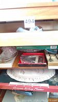 Wooden drawer containing ceramic turkey platter, glass platters, crumb brush, and knife set in boxes