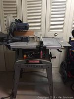 Full view of the Craftsman compound miter saw mounted on the table stand in a workshop setting. Shows overall dimensions and setup.