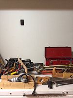Full view of toolbox and various hand tools including planes, saws, clamps, and drill power cord.