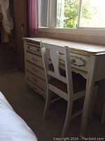 Full view of the vanity and chair next to a window