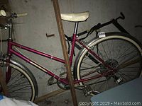 Side view of vintage ladies Royce Union bicycle in metallic pink with white seat and fenders. Shows the entire bike frame and wheels.
