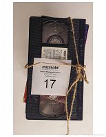 Top view of stack of 11 VHS tapes tied with string. Three tapes at top have no covers, visible tape reels inside case. Others have colorful original Power Rangers cover art.