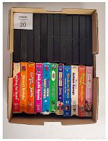 Top view of a box containing 22 VHS tapes, mostly Barney the Dinosaur titles with colorful covers showing titles and characters, some Disney VHS included.