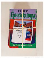 Stack of 11 paperback Goosebumps books tied with an elastic band, front book is 'Say Cheese and Die Again!' by R.L. Stine. The covers show some wear.