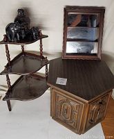 Photo of dark wood end table with closed storage door and adjacent tiered corner shelf with elephant figurines on top.