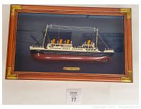 Frontal image of Titanic 3D wall art showing ship model in wood frame with decorative corner accents and brass nameplate.