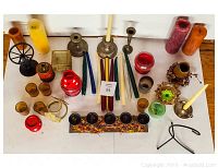 Overview of assorted candles and candle holders arranged on a wooden surface, showing variety of types, colors, and styles