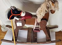 Wide view of wooden rocking horse paired with stick horse toy on wooden platform.