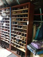 Two wooden shelving units filled with multiple pairs of men’s shoes of various styles