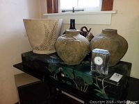Photo showing two large ceramic jugs with rustic finish, a decorative large lacquer box with floral pattern, and a Waterford crystal clock in front.