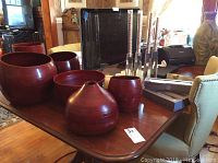 Six reddish-brown decorative wood bowls of various sizes arranged on table
