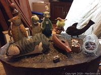 Full view of wooden and metal animal figurines, musical instrument, decorative doll, and gift box on wood table.
