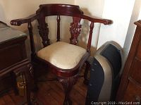 Full view of the ornate corner armchair showing overall style, wood finish, and upholstered seat.