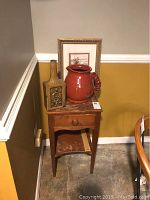 Full view of side table with ceramic pitcher, vase, and framed print on top