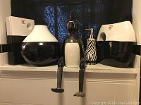 Photo of three black and white porcelain vases and wooden chicken figurine with dangling legs