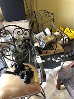 Photo showing Nikon D40x camera and Canon EOS 650 camera placed on wrought iron chairs with studio flash units and accessories around.