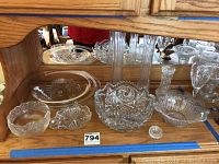 Lot of various crystal and glass items including vases, bowls and candy dishes on a wooden surface with mirror background