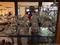 Photo of multiple crystal stemware glasses featuring etched patterns arranged on a glass shelf.