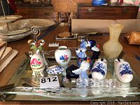 Wide shot of all the items on glass tray showing Delft figurines, vases, pie server and small decorative ceramics.