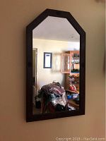 Full view of wooden wall mirror showing rectangular shape with arched top and dark wood frame.