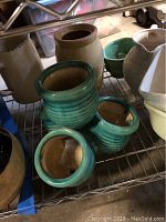 Various pottery vases, bowls and pitchers arranged on a metal shelving unit