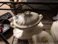 Large salt-glazed tureen with handle lid and matching platter, showing ribbed design and off-white color.
