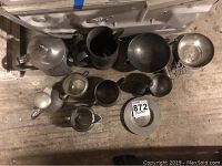 Photo showing multiple pewter items on a surface including coffee pot, pitcher, creamer, small cream and sugar set, and additional pieces illustrating overall quantity and condition.