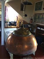 Front view of large copper dome-shaped hanging light fixture in a room setting, showing the patinated surface and brass top fitting.