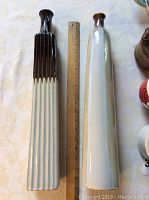 Two tall pottery vases positioned upright beside a ruler showing approximate height of 18 inches.