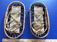 Pair of two vintage Bear Paw snowshoes laid side by side on a blue background. Measuring ruler placed below for scale indicating 18 inches length and 9 inches width.