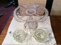 Front view of the 9-inch glass crystal cake plate elevated on its pedestal, with a creamer and sugar bowl in front on a cloth.